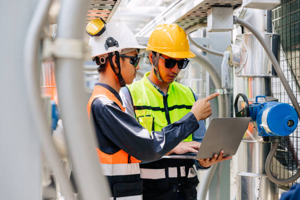 Two engineers reviewing project plans on a laptop